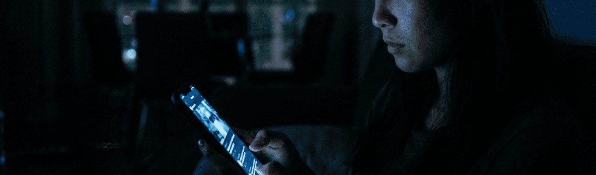 Pessoa olhando a tela do celular no escuro